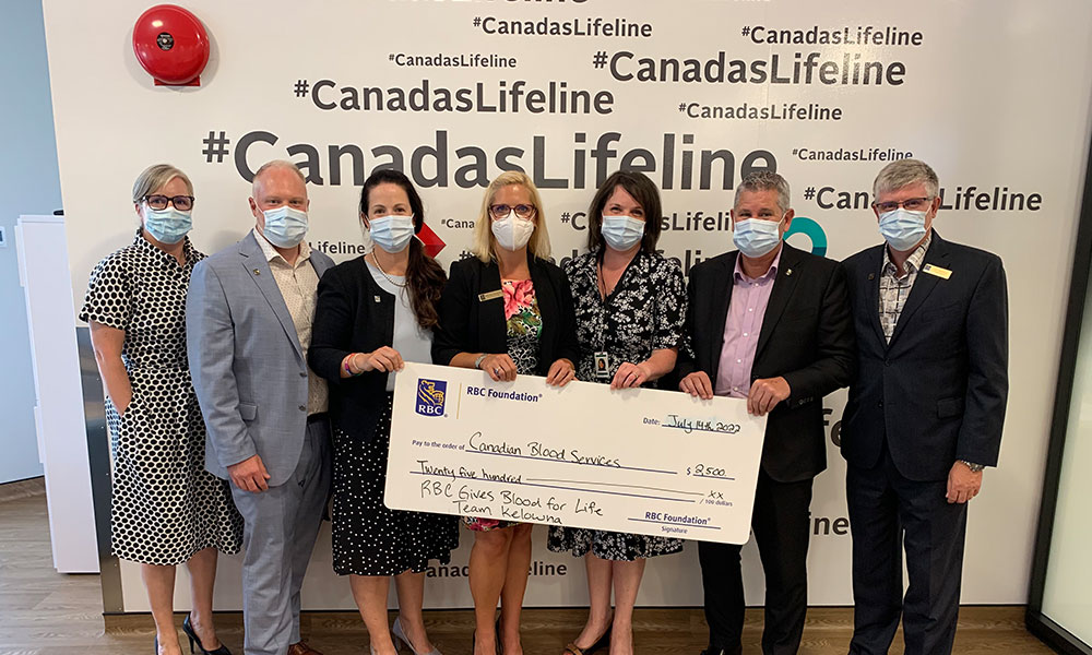 RBC employees hold a cheque to Canadian Blood Services in a donor centre
