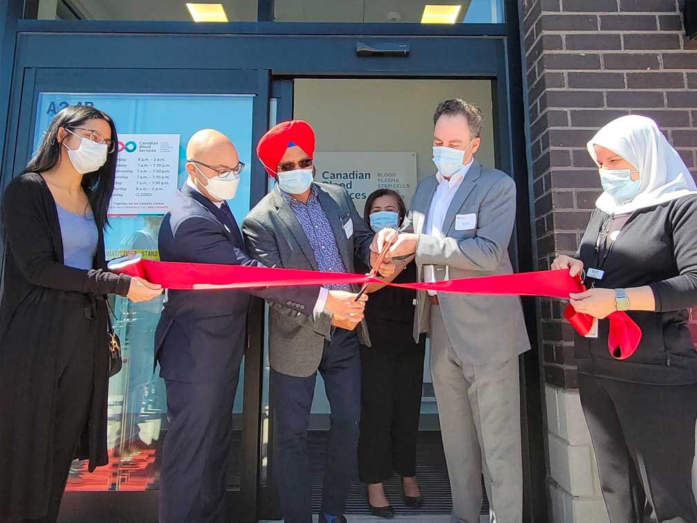 A group of people cut a ribbon to open a new plasma donor centre