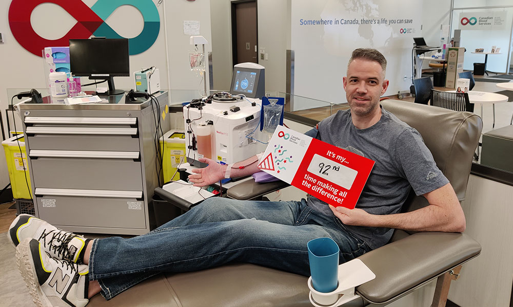 man lying on a donor chair and holding a sign