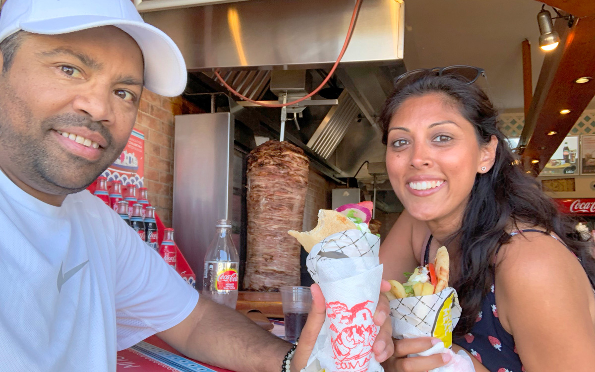 Salim and Rabia smile at the camera while enjoying local fare at a restaurant in Greece
