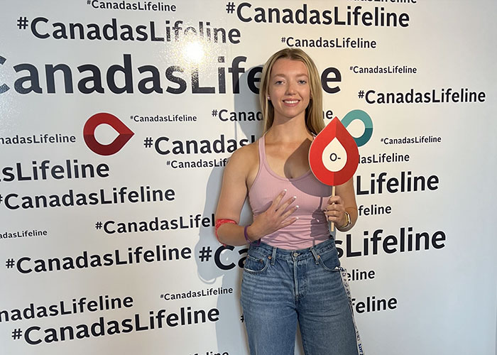 Woman standing holding a blood drop sign
