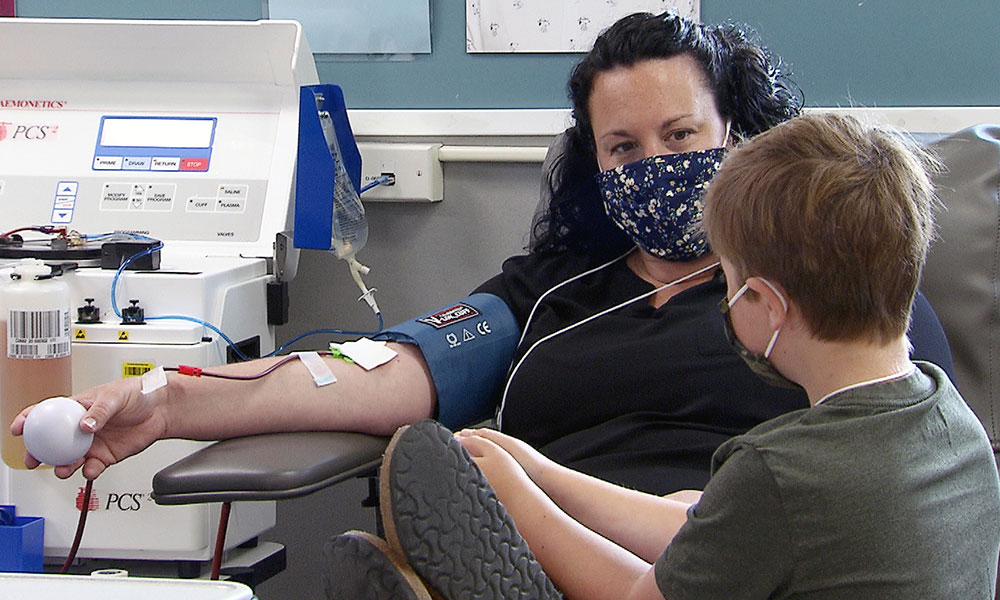 Plasma donor looking at her young son while she donates plasma