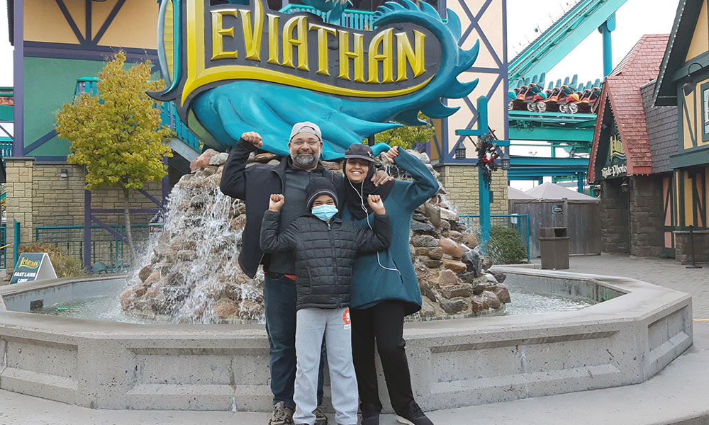 Man and two children in front of fountain at amusement park