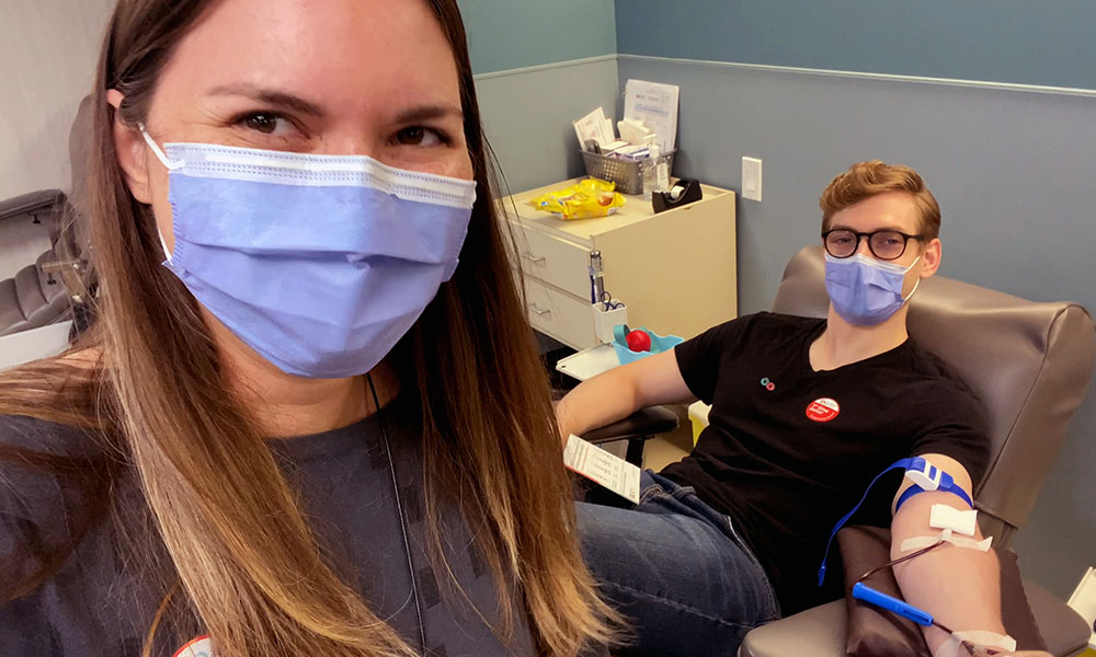Blood donor looking at camera next to her husband donating blood