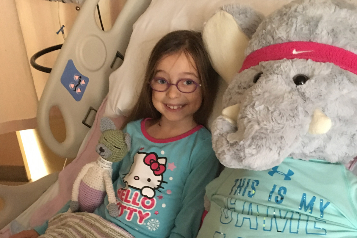 Girl laying in hospital bed, smiling