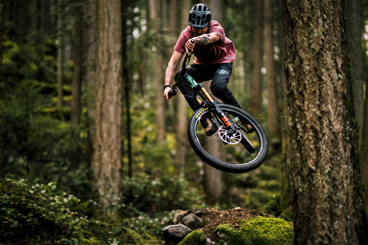 Rider in mid-air after a jump on a forest trail