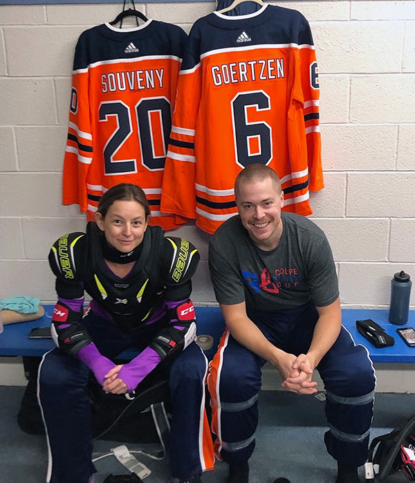 Blood recipient and her fiancé sitting on a bench with their hockey jerseys behind them.