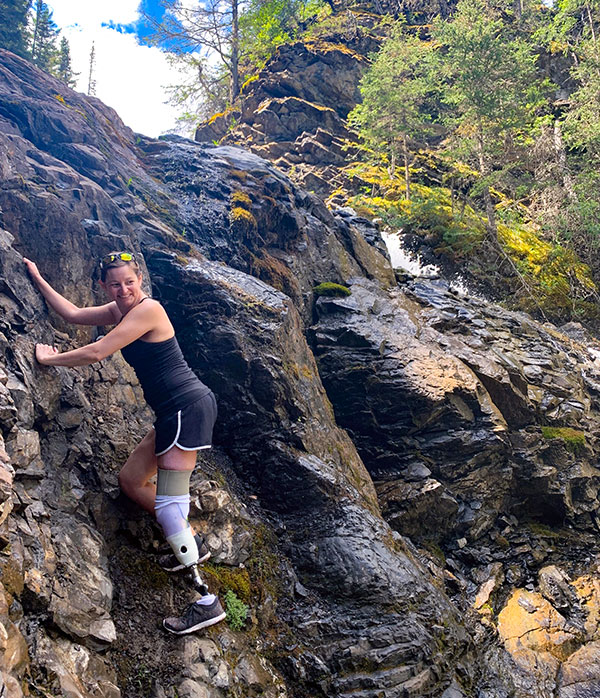 Woman with left leg prosthetic scaling a rock face