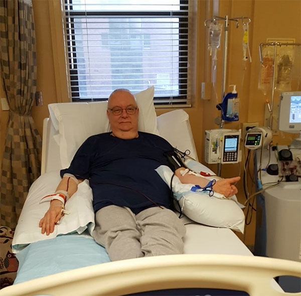 A man lays in a hospital bed, donating stem cells