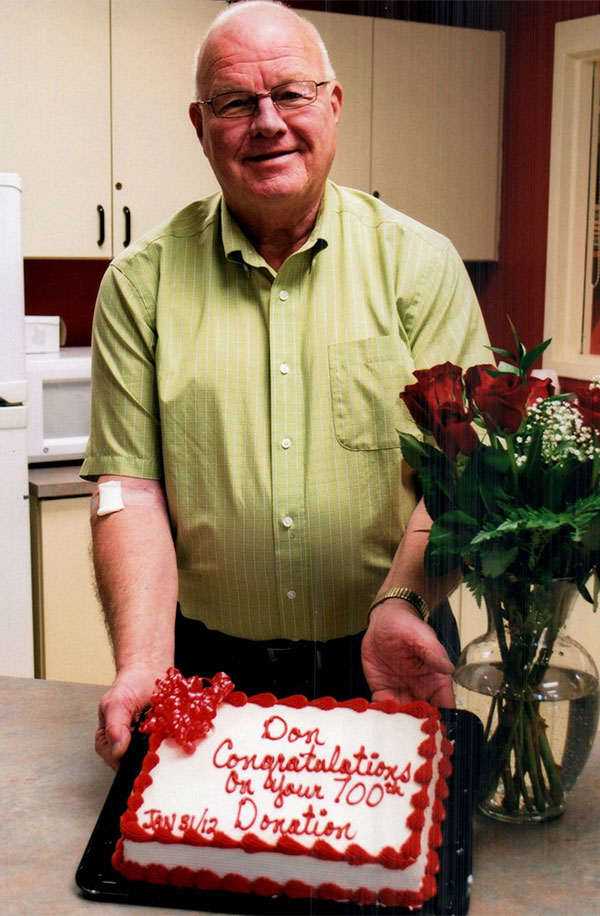 Man standing with a cake that says “Don, congratulations on your 700th donation”