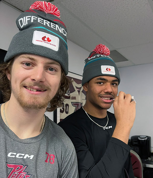 Hockey player swabs inside of cheek with cotton swab, with teammate beside him