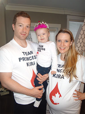 Man holding a female toddler posing for a photo next to a woman