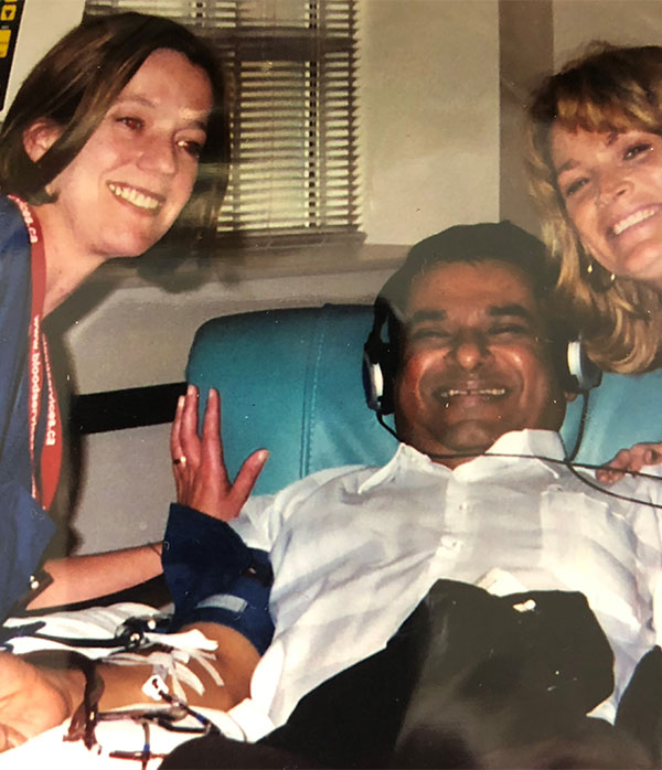 A blood donor in donation chair with donor centre staff