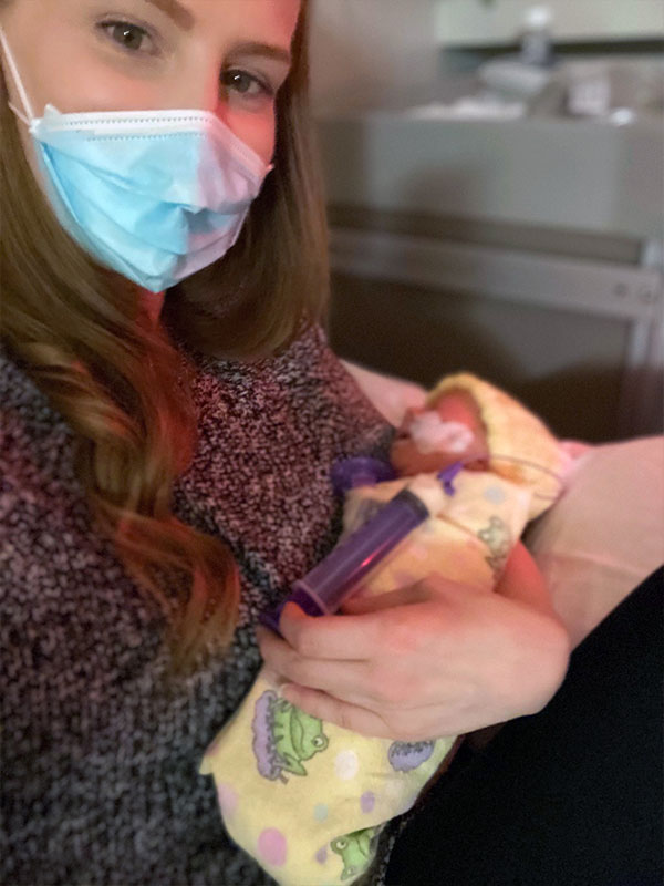 Woman in hospital with infant son with breathing tube on her chest