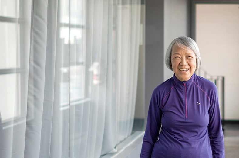 Wai Yin in a purple shirt walking through a hallway