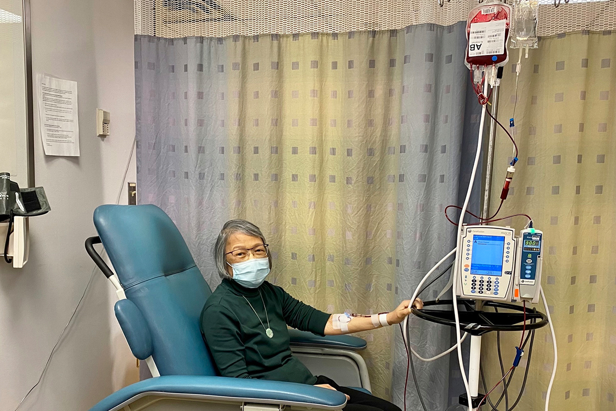 A woman in a chair at a hospital receiving a blood transfusion.