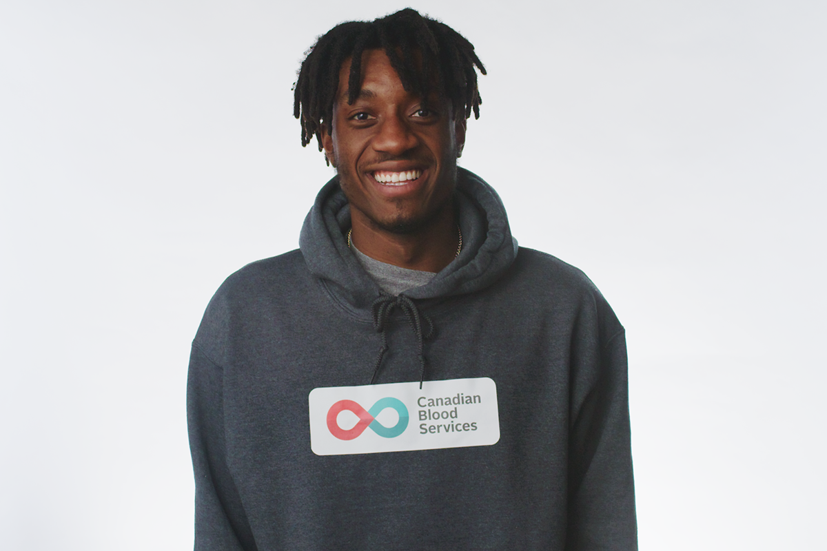Hockey Gives Blood Player Ambassador Zack Stringer smiles in a Canadian Blood Services pullover hoodie