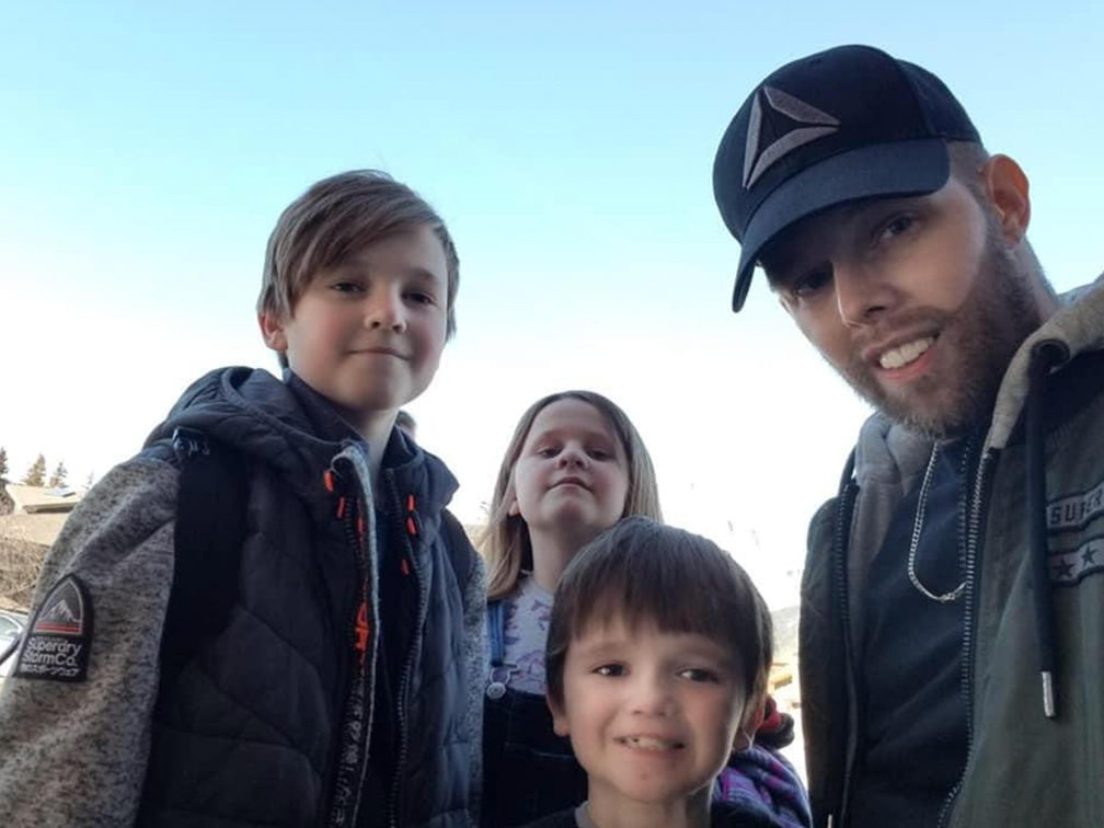 Three young children and their father smiling into the camera