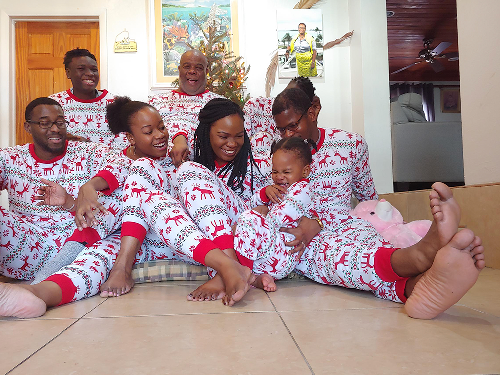 Eight family members laughing and wearing matching holiday pyjamas with reindeer and snowflake pattern.