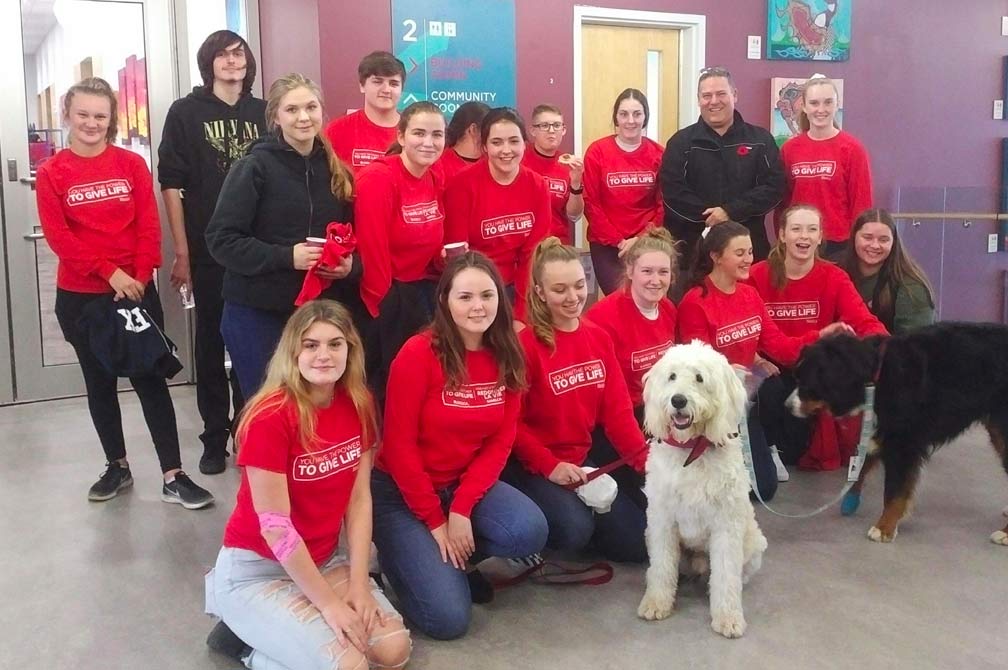 A group of students pre-COVID at a blood donor event with therapy dogs