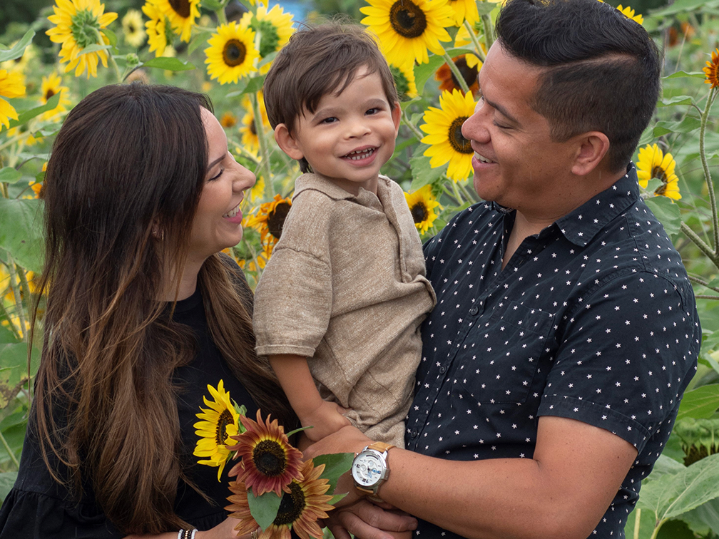 Man and woman holding their son in sunflower field