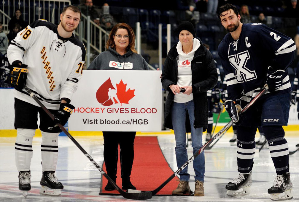 Stem cell transplant recipient Gail Stewart posing for ceremonial puck drop at X-Men’s ice hockey game