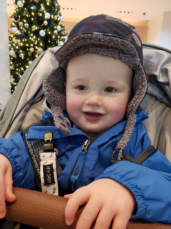 Image of Charlie, Elaine’s son wearing a blue jacket and a grey tuque sitting in a baby seat