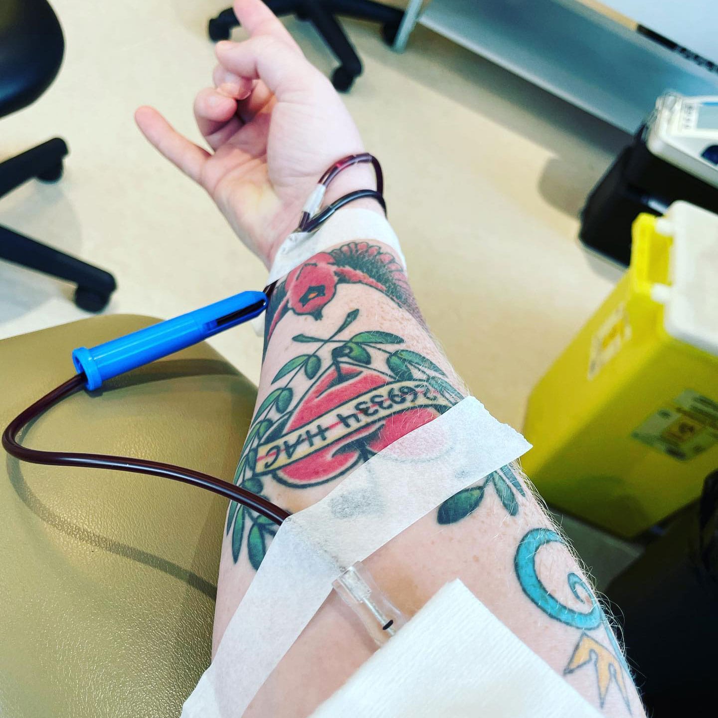 Arm with tattoos giving blood donation
