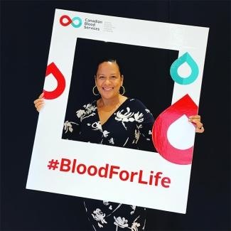 Anika McDonald, a Black employee at Canadian Blood Services holds a branded #BloodForLife photo frame. Anika is proud to be contributing to her organization’s efforts to promote diversity and inclusion.  