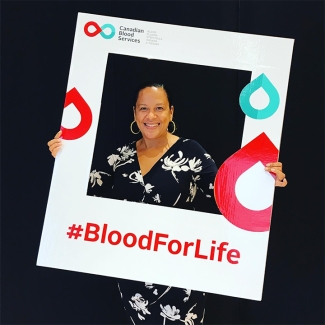 Anika McDonald, a Black employee at Canadian Blood Services holds a branded #BloodForLife photo frame. Anika is proud to be contributing to her organization’s efforts to promote diversity and inclusion.