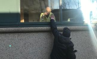 Albert's son John visiting him through a window during Covid-19