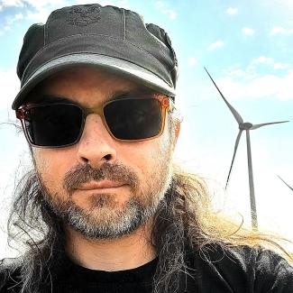 Blood donor in hat in front of wind turbine