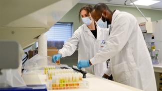 Image of Carissa Kohnen and Andy Tshiula Kalenga working with samples and preparing for testing.