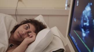 Image of Dr Shelly Sarwal lying in a hospital bed with a machine of her ultrasound