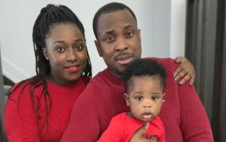 Akintunde Adeniyi with his wife and son in red clothing, pose on the stairs of their home.