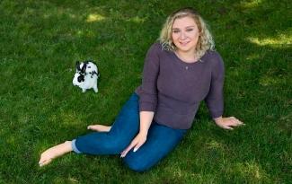 Cayleigh Kearns, who has common variable immune deficiency (CVID) sits on the grass with her pet rabbit.