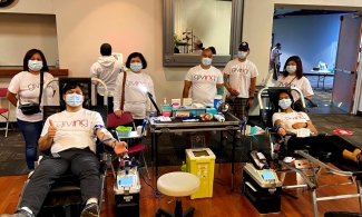 Two members of Iglesia Ni Cristo (Church of Christ) in Milton donate blood at an event with other participants gathered behind them.