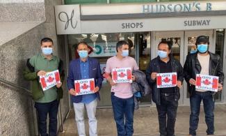 Members of the Nepalese Blood Donors Association hold signs with the Canadian flag that say “I am a blood donor” outside a Canadian Blood Services donor centre in Toronto, Ont.