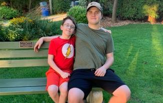 Nolan Clark sits on a park bench with his arm around his younger brother Nicholas Clark. Nolan donated blood for the first time after Nicholas had blood transfusions as an infant.