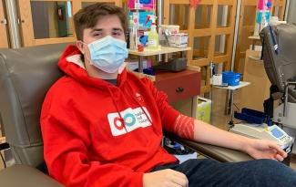 Nolan Clark, a teenage boy wearing a red Canadian Blood Services hoodie, donates blood for the first time.