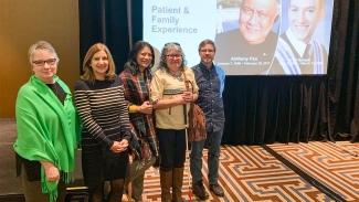 Image of Denice Klavano, Susan Harason, Kathleen Tabinga, Shirley Sinclair and Dr. Paul Postuma pictured together in front of a Patient & Family Experience presentation