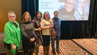 Image of Denice Klavano, Susan Harason, Kathleen Tabinga, Shirley Sinclair and Dr. Paul Postuma pictured together in front of a Patient & Family Experience presentation