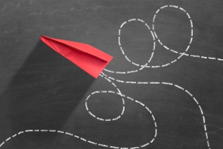 Image of a paper airplane with dotted lines around it on a grey chalkboard background