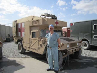 Dr. Andrew Beckett Image of Dr. Andrew Beckett standing beside military ambulance