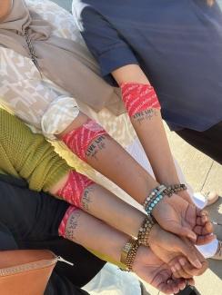 A group of hand together, showing arm bandages and matching tattoos that say "live life give life" after donating blood