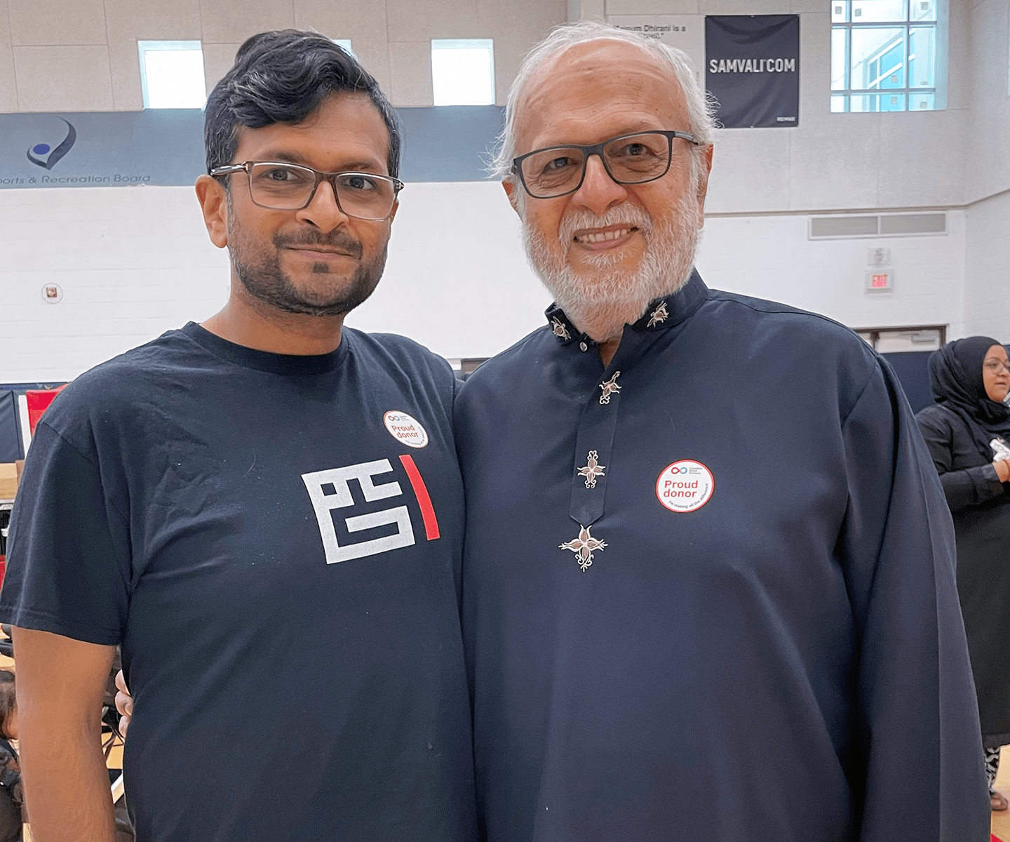 Father and son wearing “proud donor” stickers at blood donation event 