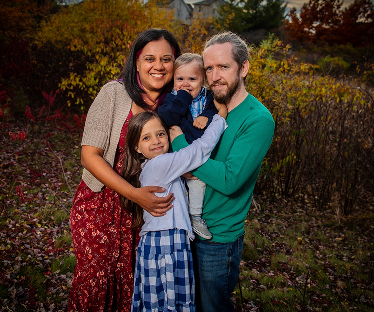family of four hugging outdoors