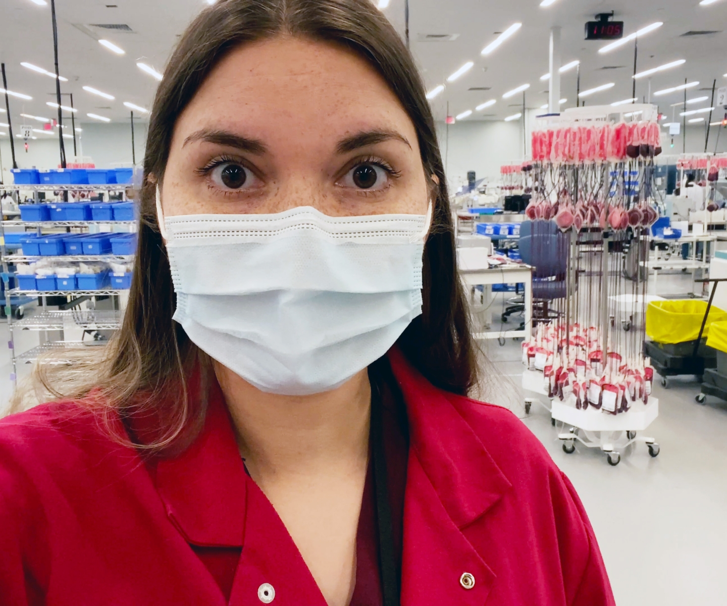 Une docteure en blouse rouge face à un centre de production de sang