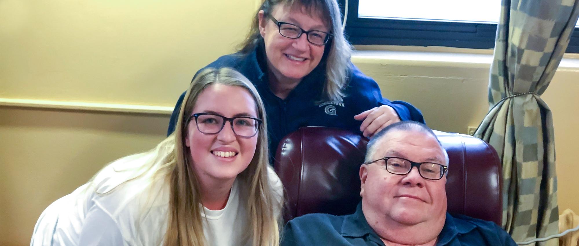 Image of Bruce Phinney with wife and daughter sitting in a recliner