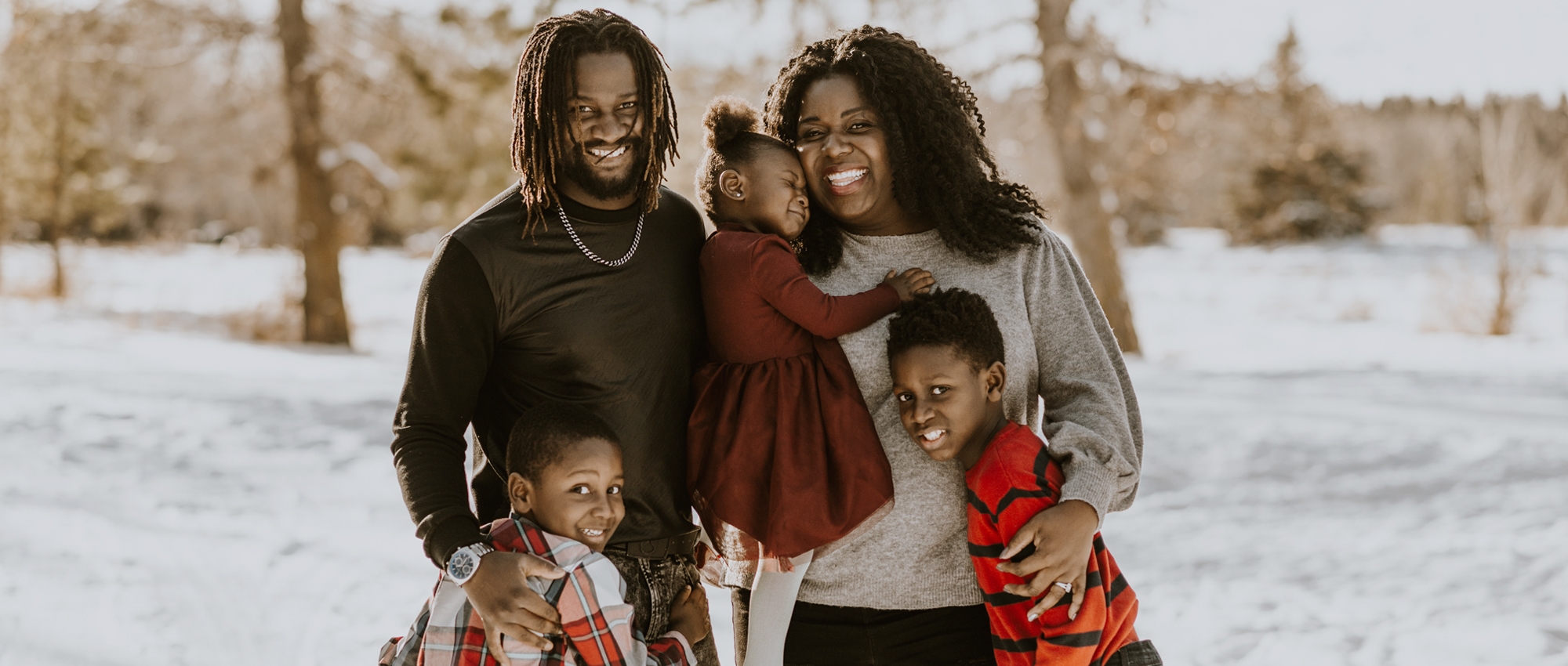 A child who had blood transfusions is held by her parents who are blood donors, as they pose for a photo outside in winter with the child’s two brothers.